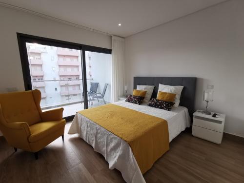 - une chambre avec un lit, une chaise et une fenêtre dans l'établissement Cool Residence, à Portimão