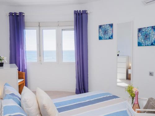 - une chambre avec des rideaux violets et un lit offrant une vue sur l'océan dans l'établissement Apartment on Beach Mijas 2, à Sitio de Calahonda