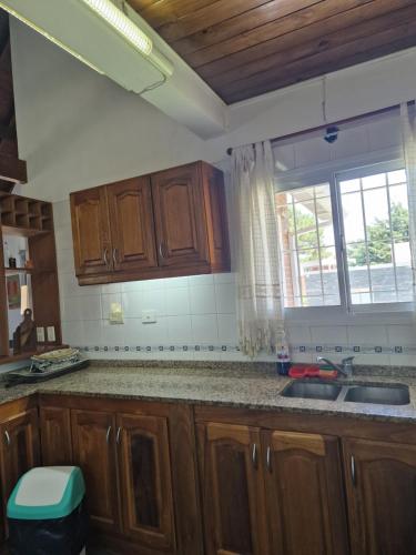 a kitchen with wooden cabinets and a sink and a window at Dunas Chalet y Apartamento, sólo familias in Pinamar