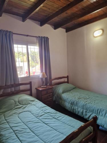 two beds sitting in a room with a window at Dunas Chalet y Apartamento, sólo familias in Pinamar