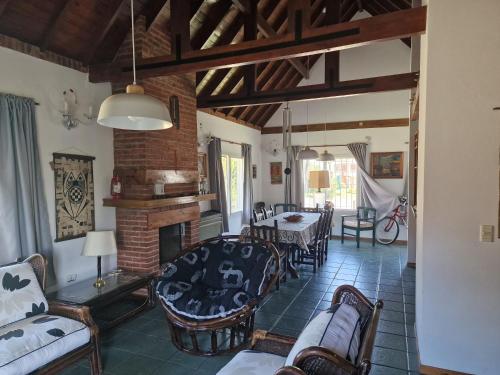 a living room with a fireplace and a table and chairs at Dunas Chalet y Apartamento, sólo familias in Pinamar