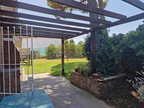 a patio with a wooden pergola and a swing at Dunas Chalet y Apartamento, sólo familias in Pinamar