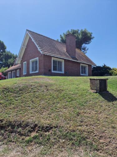 a house on top of a grassy hill at Dunas Chalet y Apartamento in Pinamar