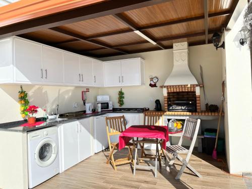 a kitchen with white cabinets and a table and chairs at Slice of ponta do sol Room 1 in Ponta do Sol