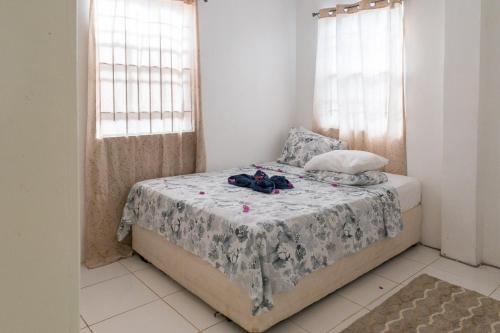 a bedroom with a bed with a white blanket and two windows at Caribbean Dream Vacation Property CD1 in Gros Islet