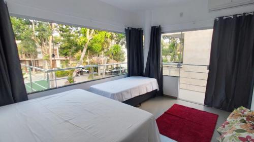 - une chambre avec 2 lits et une grande fenêtre dans l'établissement Quatro suítes com piscina,1,7 km do centro de Arraial, à Arraial d'Ajuda