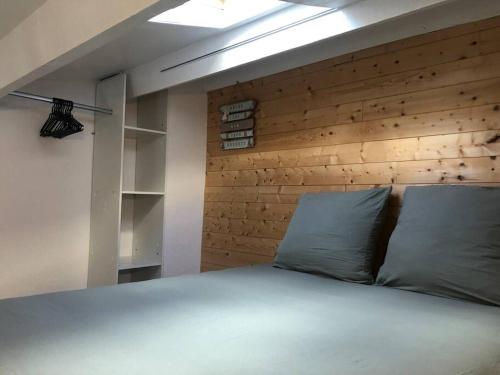 1 dormitorio con 1 cama con pared de madera en Joli appartement à proximité du village naturiste en Cap d'Agde