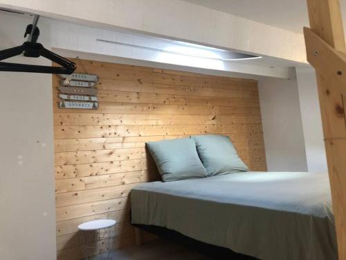 Cama en habitación con pared de madera en Joli appartement à proximité du village naturiste en Cap d'Agde