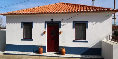 a white and blue house with a red door at CASA NA ALDEIA in Estremoz