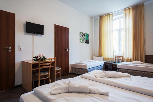 um quarto de hotel com duas camas e uma secretária em Queens Park Hotel em Berlim
