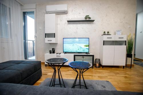 uma sala de estar com um sofá e uma televisão de ecrã plano em Tik Tak apartman em Subotica