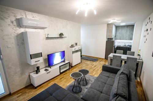 uma sala de estar com um sofá e uma televisão em Tik Tak apartman em Subotica