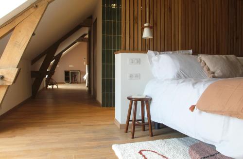 een slaapkamer met een groot wit bed en een kruk bij Allée des noyers in Saint-Michel-de-Bannières