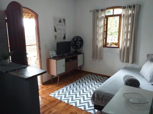 a bedroom with a bed and a desk and a television at Casa com vista para o mar em Paraty in Paraty