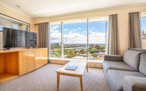 a living room with a couch and a large window at Holiday Inn Sydney Potts Point in Sydney