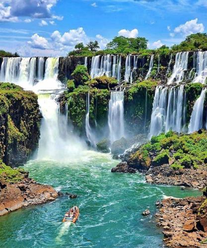 un barco en un río frente a una cascada en Deptos Doña Benigna en Puerto Iguazú