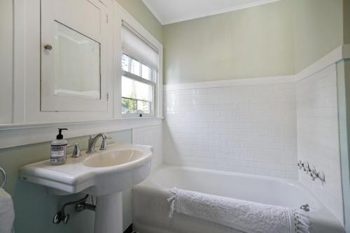 een witte badkamer met een wastafel en een bad bij Bush Park & Downtown Charmer in Salem's Best Location in Salem