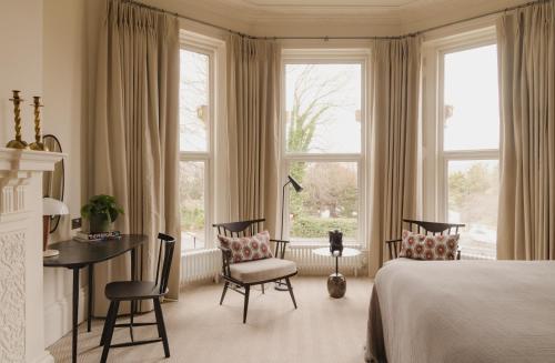 a bedroom with a bed and a desk and windows at Leighton House - Boutique Guesthouse in Bath