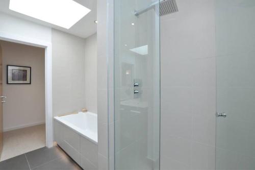 a white bathroom with a shower and a sink at Central London Luxury 4 Bed Home in London