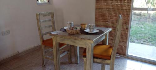 a wooden table with two chairs and a table with two cups at Bella vista a las sierras in Merlo
