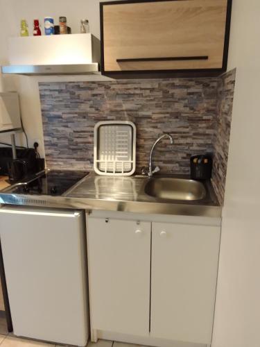 une cuisine avec un évier et un micro-ondes dans l'établissement chez LOLO, à Saint-Nazaire