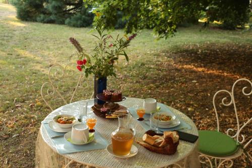 - une table avec de la nourriture et des boissons ainsi qu'un vase de fleurs dans l'établissement La Closerie de l'Autan, à Fenouillet
