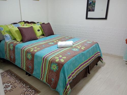 un letto con coperta colorata e cuscini sopra di Araucarias Inn 2 a Santa Rosa de Cabal