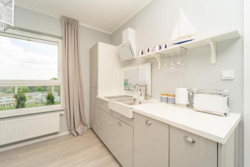uma cozinha branca com um lavatório e uma janela em Apartament z tarasem i widokiem na morze - The View - Gdańsk Brzeźno em Gdansk