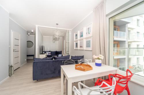 uma sala de estar com um sofá azul e cadeiras vermelhas em Apartament z tarasem i widokiem na morze - The View - Gdańsk Brzeźno em Gdansk