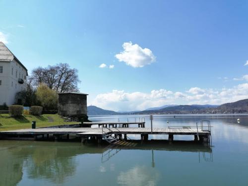 a dock on the water next to a building at BaMo Studio - modern living lakeside in Klagenfurt