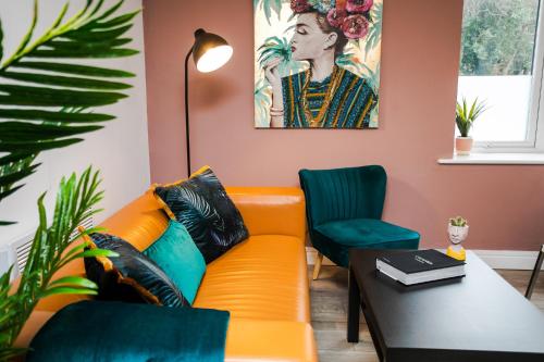 an orange couch in a living room with a table and chairs at Fab 2bedroom apartment- Free parking, 5mins from city centre, Portland Rd NE2 1DJ in Newcastle upon Tyne