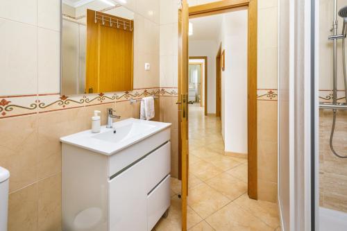 a bathroom with a white sink and a mirror at Apartamento Monarquia - T3 Quarteira in Quarteira