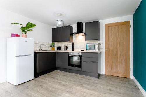 a kitchen with black and white appliances and a white refrigerator at Fab 2bedroom apartment- Free parking, 5mins from city centre, Portland Rd NE2 1DJ in Newcastle upon Tyne