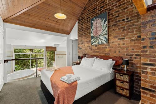 a brick walled bedroom with a bed and a window at Hunchy Hideaway in Montville