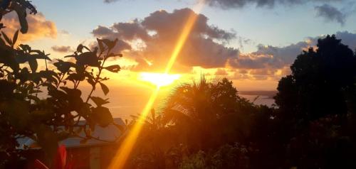 um pôr-do-sol sobre o oceano com o sol no céu em "SunRise Inn" Nature Island Dominica 