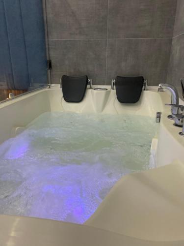 uma banheira cheia de água azul ao lado de um lavatório em SpaNish apartman em Niš