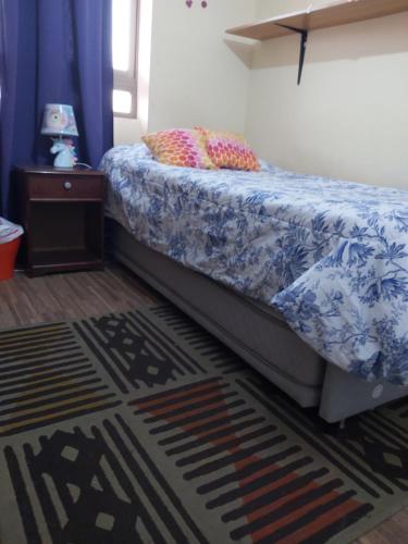 a bedroom with a bed with a blue and white comforter at Habitación frente al mar in Iquique