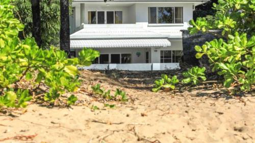 a white house on the beach with trees at Seabreeze Beachfront - Clifton in Clifton Beach