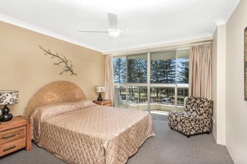 a bedroom with a bed and a chair and a window at Cashelmara Burleigh - Hosted by Burleigh Letting in Gold Coast