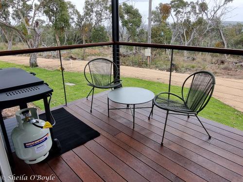 two chairs and a table on a deck with a grill at Glen Lough Cabins in Glen Aplin