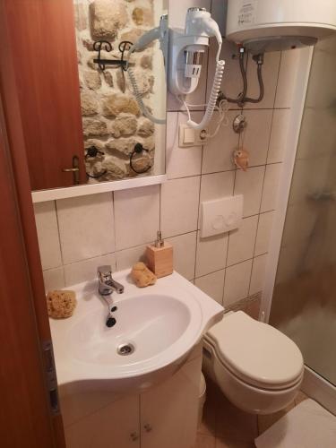 La salle de bains est pourvue d'un lavabo et de toilettes. dans l'établissement Room Ivana, à Rab