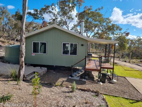 a green tiny house with a porch at Glen Lough Cabins in Glen Aplin