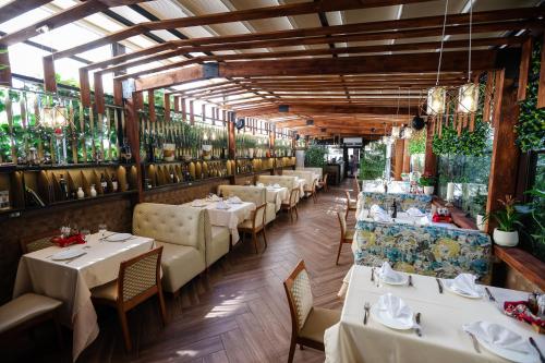 a restaurant with white tables and chairs and plants at Vila Ferdinand Modern Rooms In Tirana's Center in Tirana