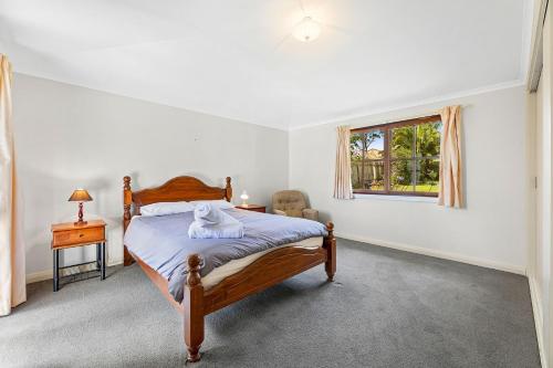 ein Schlafzimmer mit einem Bett, einem Stuhl und einem Fenster in der Unterkunft 12 Bluewater Drive Narooma in Narooma