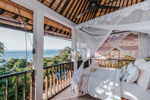 a bed on a balcony with a view of the ocean at Villa Mimpi Manis in Nusa Lembongan