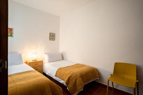 1 dormitorio con 2 camas y silla amarilla en Trendy Homes Casa Nerida, en Rodalquilar