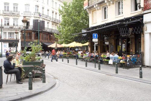 a street with people sitting on benches in a city at Atlas Hotel Brussels in Brussels