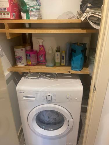 lavadora y secadora en una habitación con estanterías en Homely abode, en Croydon