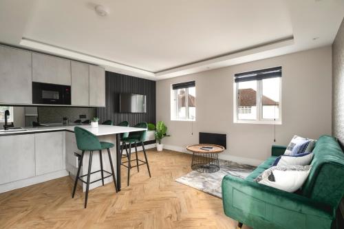 a living room with a green couch and a kitchen at Skyvillion - COZY LARGE 4 Bed Apartments in London Enfield, Mins to Tube Station, Free Wi-Fi in Cockfosters