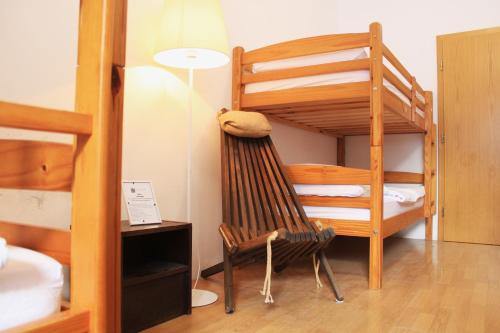 Cette chambre dispose de lits superposés, d'une chaise et d'une échelle. dans l'établissement Hostel Kronotop in Triglav National Park, à Log pod Mangartom